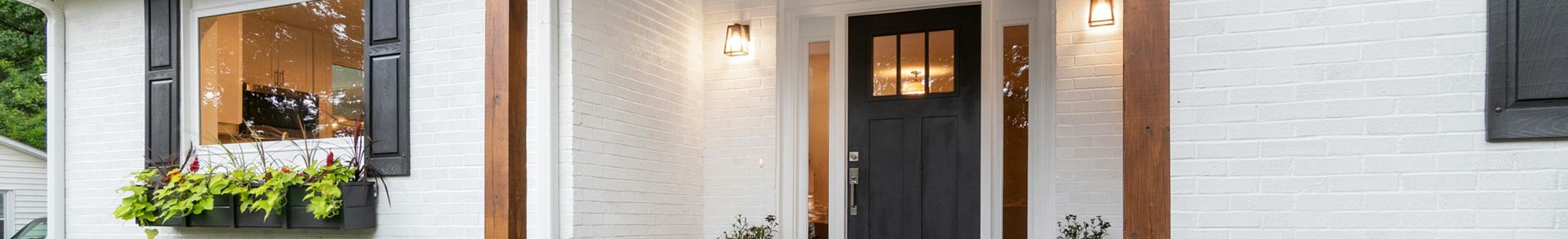 Front view of a charming white brick suburban house with black accents.